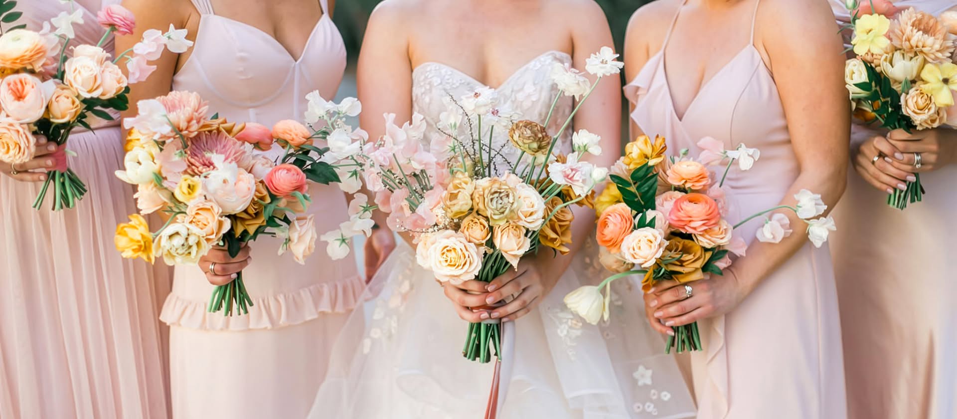 A bride and her bridesmaids holding peach and blush bouquets at a San Diego wedding, planned by Bliss Events.