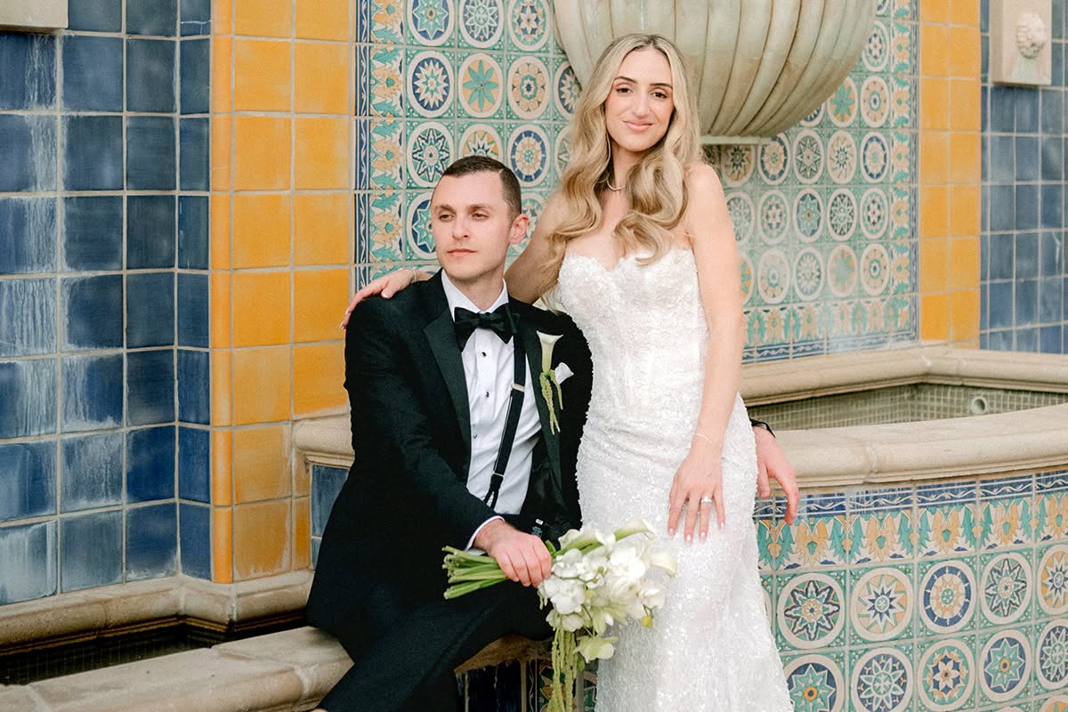 Alex and Cory posing at a fountain framed by blue and gold Spanish-style tile.