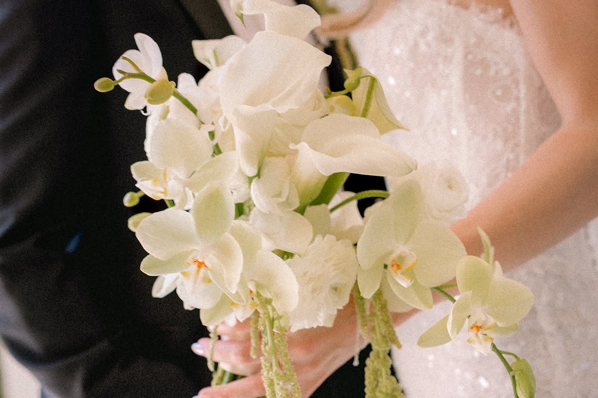Bridal bouquet of white orchids and calla lilies with trailing green amaranthus.