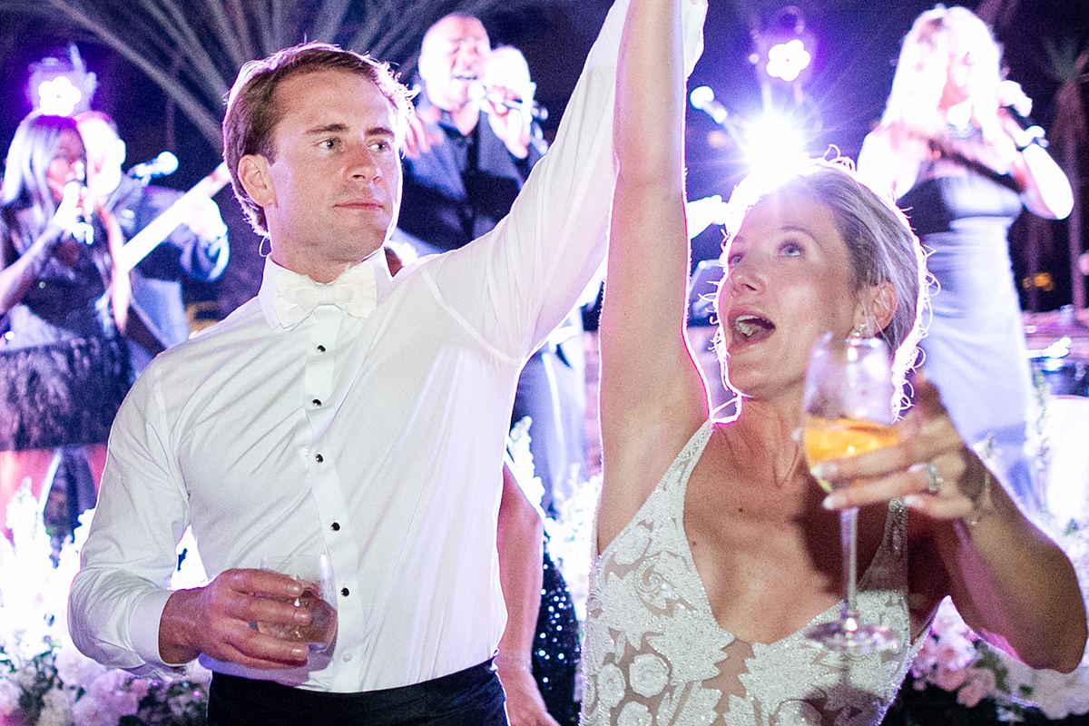 Claire and Collin celebrating on the dance floor, the bride in a beaded reception dress as the band plays.
