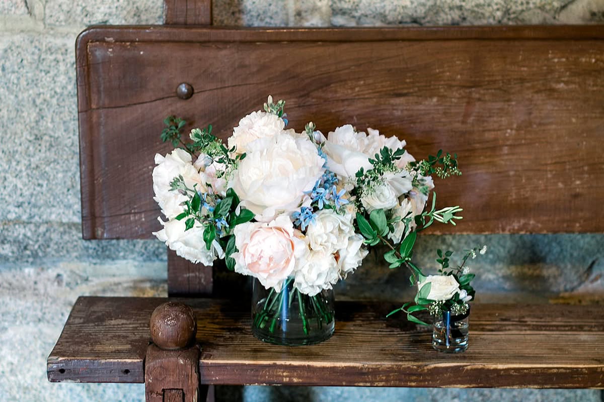 White floral bouquet arranged on a rustic wooden bench.