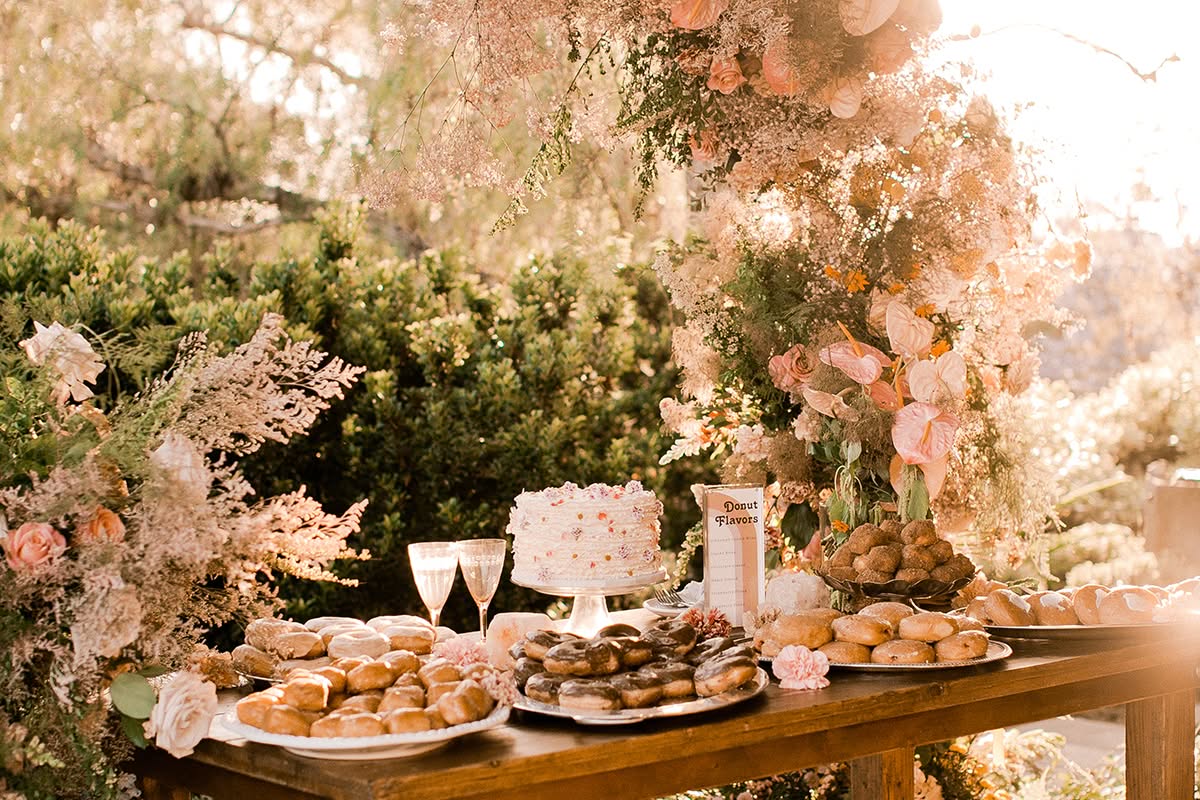 Dessert table with floral arrangements, cake stands, and warm garden wedding decor at a private residence.