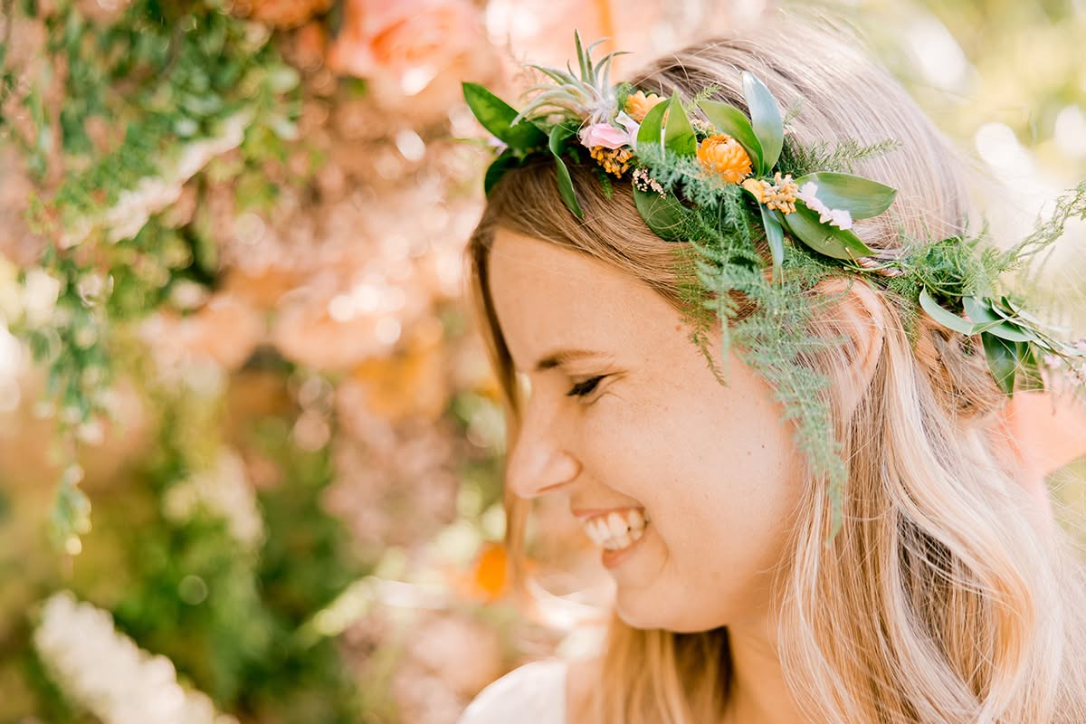 Bride smiling in a floral crown during a garden wedding portrait.
