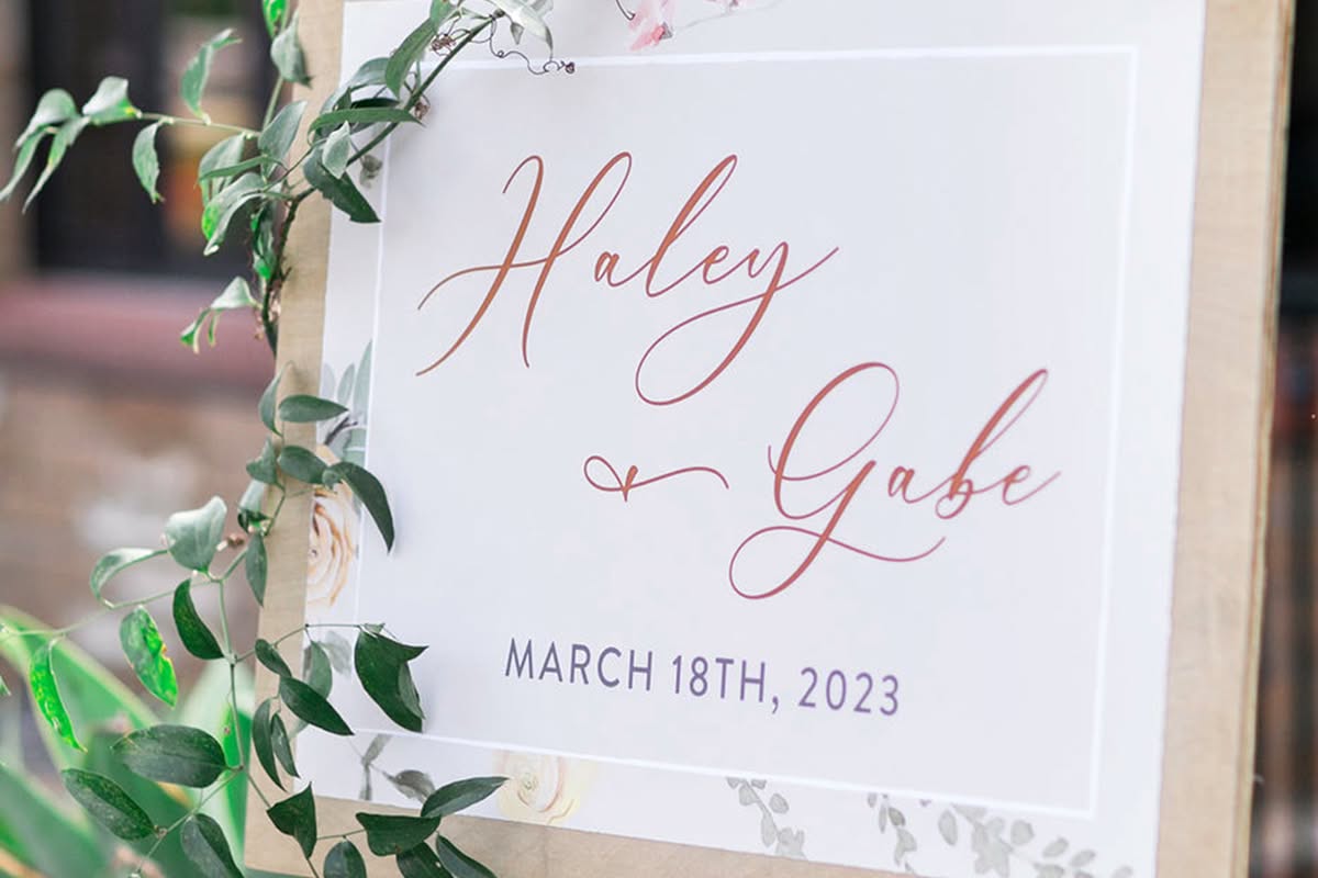 Wedding welcome sign for Haley and Gabe accented with greenery.