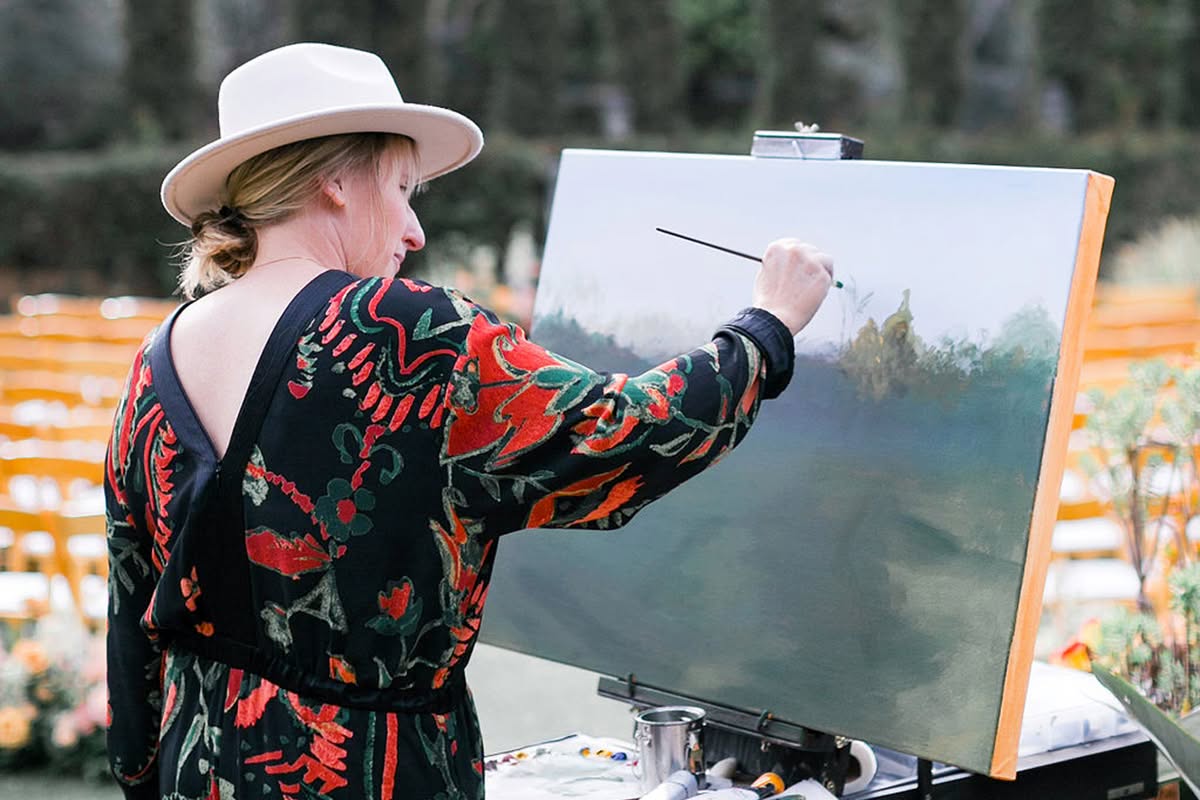 Live painter creating artwork during an outdoor wedding ceremony.