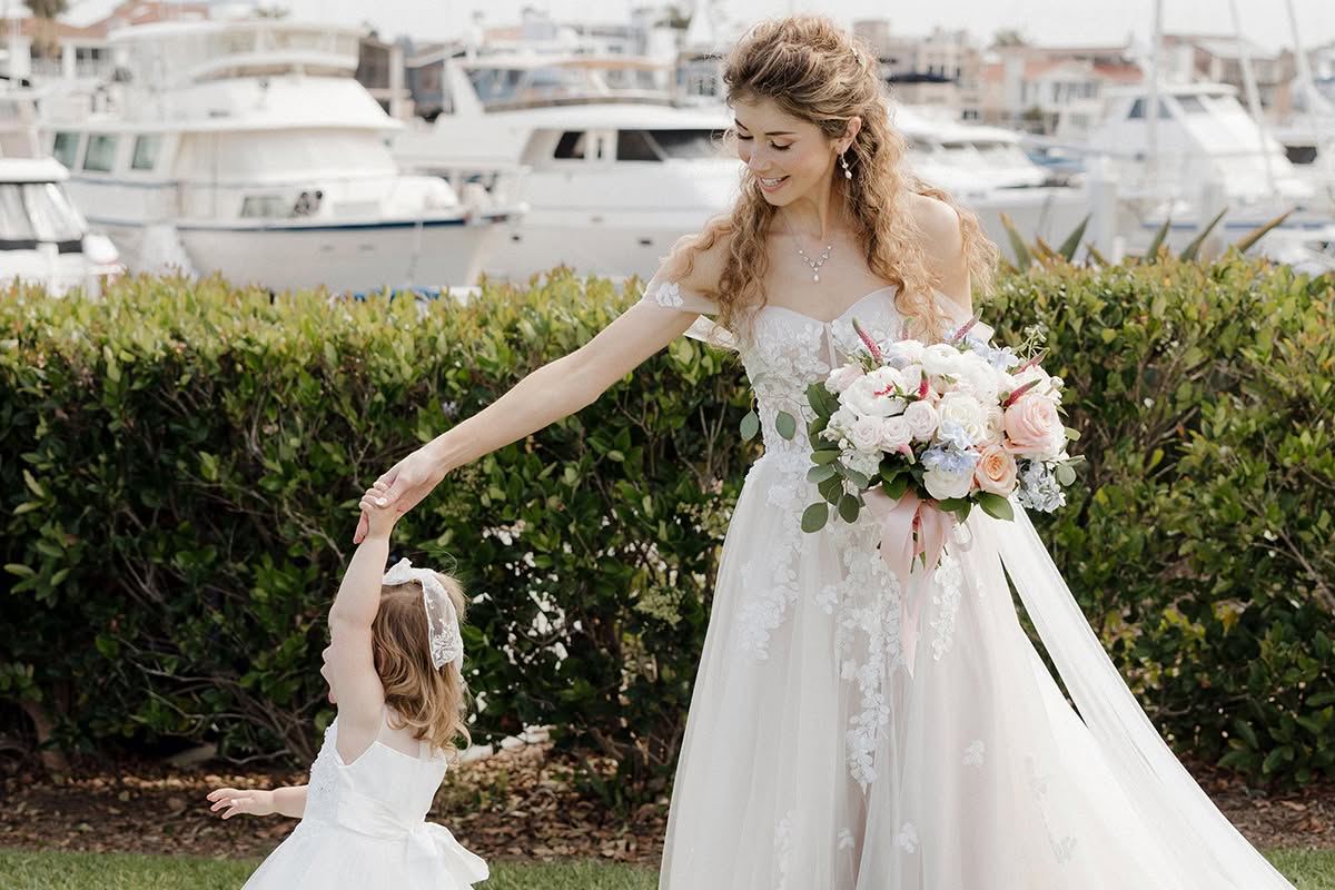 Bride holding hands with a flower girl near the marina before a Coronado wedding ceremony.