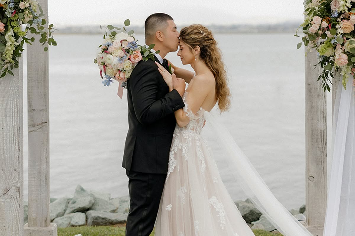 Waterfront wedding ceremony at Loews Coronado Bay Resort with a floral arch and seated guests.