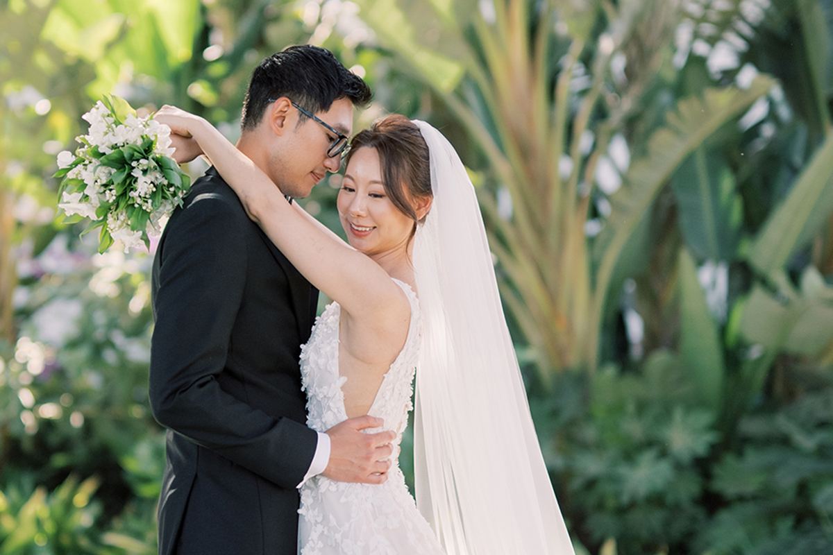 Bride and groom sharing a quiet garden portrait surrounded by tropical greenery.