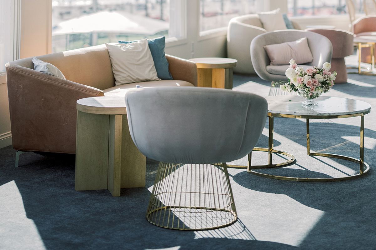Lounge seating with ocean-view windows, soft velvet chairs, and a crystal chandelier.