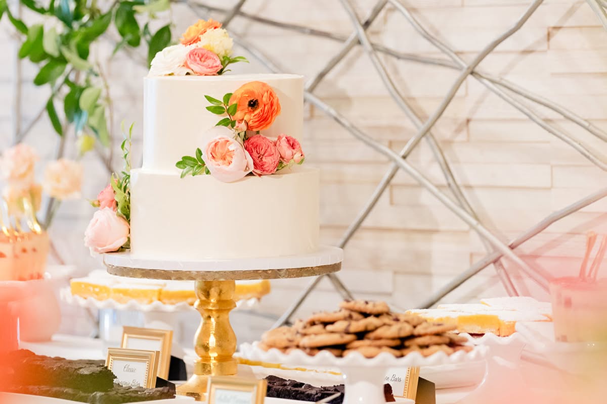 White wedding cake with bright orange, pink, and yellow floral accents at Estancia La Jolla Hotel & Spa.