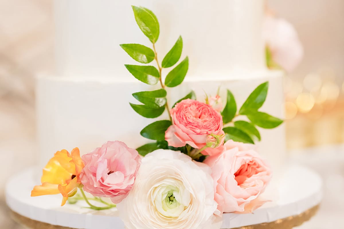 Wedding cake and dessert display with colorful floral accents at Estancia La Jolla Hotel & Spa.