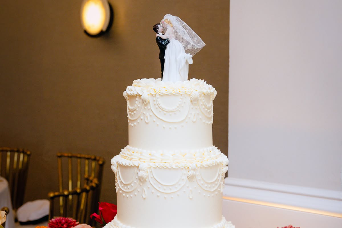 White tiered wedding cake displayed with colorful flowers.