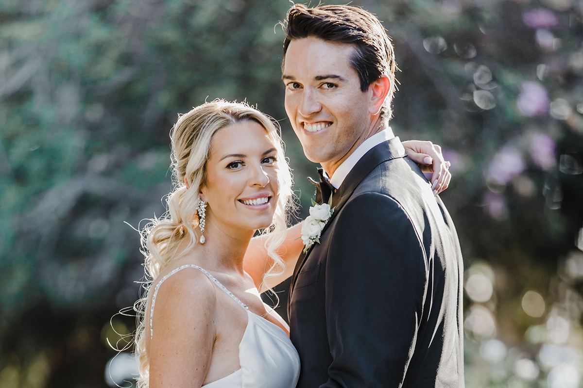 Bride and groom posing together outdoors during their L’Auberge Del Mar wedding.