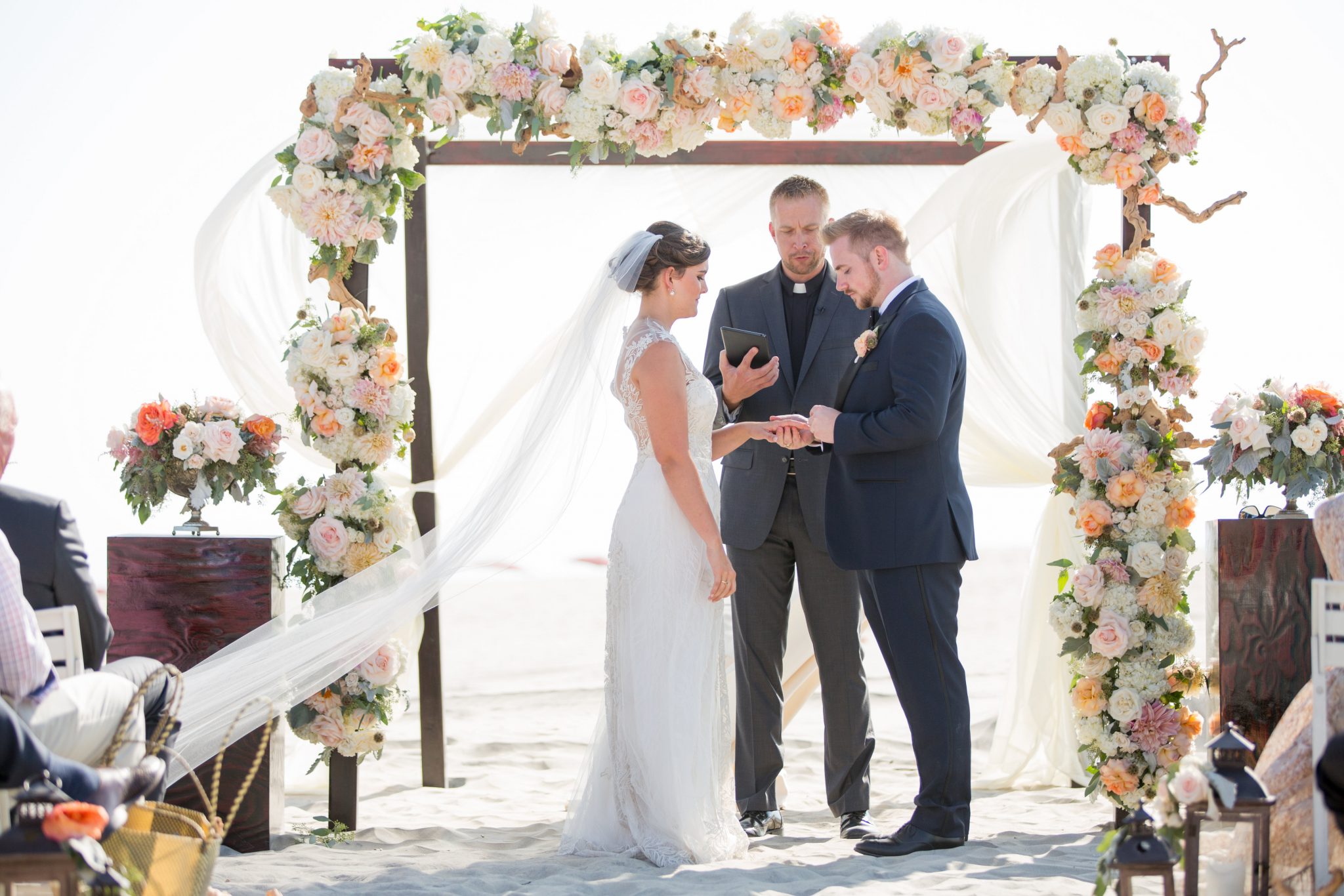 Leslie and Noah standing under their wedding arch during their beach wedding
